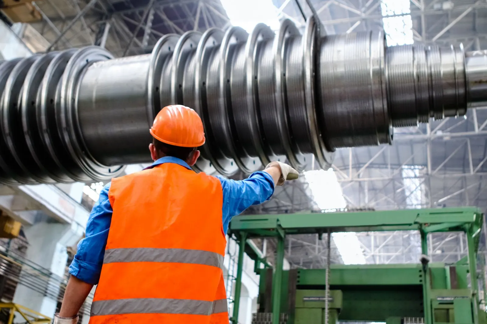 Técnico com colete e capacete inspecionando equipamento industrial