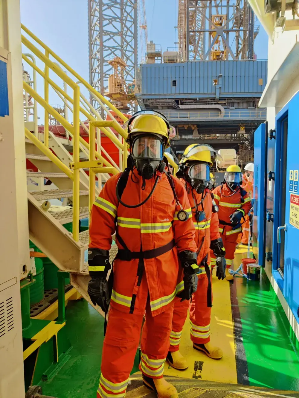 Equipe com máscara respiratória e EPI completo em plataforma offshore
