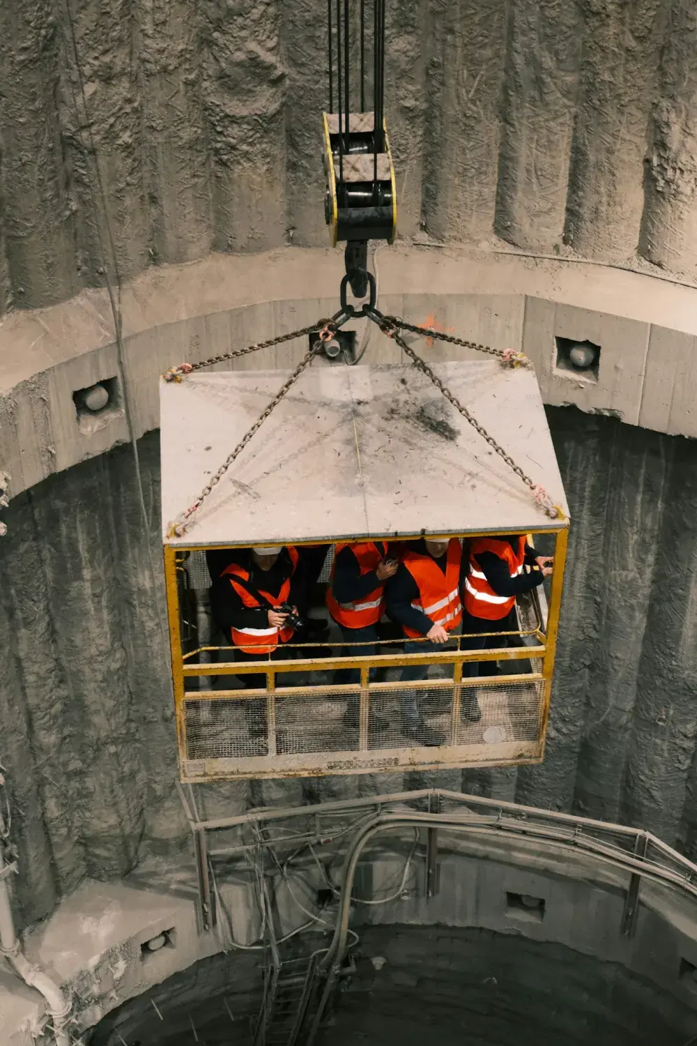 Equipe descendo por guindaste em poço de concreto