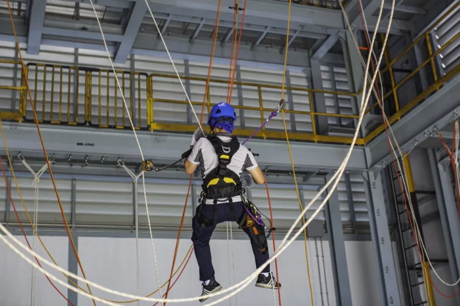Técnico em treinamento de acesso por corda em estrutura de rig indoor